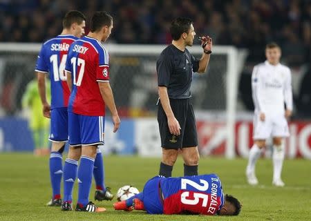 FC Basel's Derlis Gonzalez (C) lies on the ground next to referee Milorad Mazic during their Champions League Group B soccer match against Real Madrid at St. Jakob-Park stadium in Basel November 26, 2014. REUTERS/Arnd Wiegmann