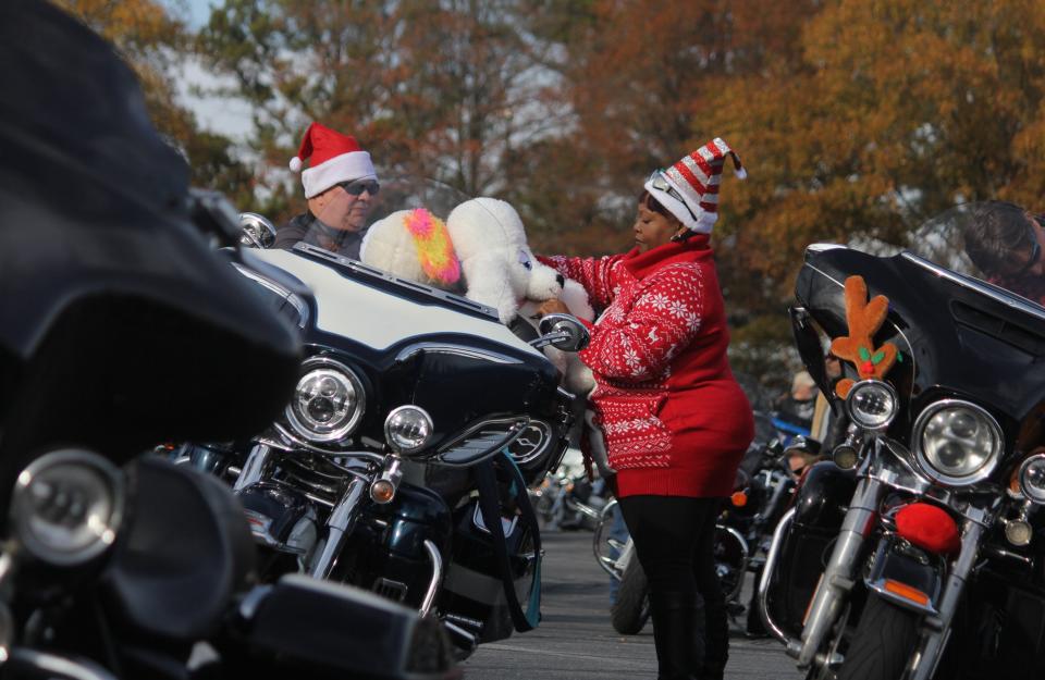 Angela Highhouse and Jimmy Highhouse wrestle two stuffed animals off their motorcycle, to donate to children, after riding in the 41st annual Anderson Toy Parade on Nov. 28, 2021.