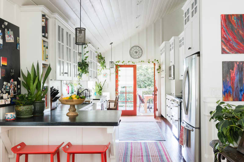 A unique spin on a farmhouse kitchen, with vaulted ceilings and red accents, like a red windowed door and red stools