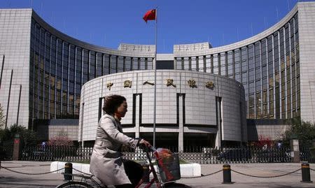 A woman rides past the headquarters of the People's Bank of China (PBOC), the central bank, in Beijing, April 3, 2014. REUTERS/Petar Kujundzic