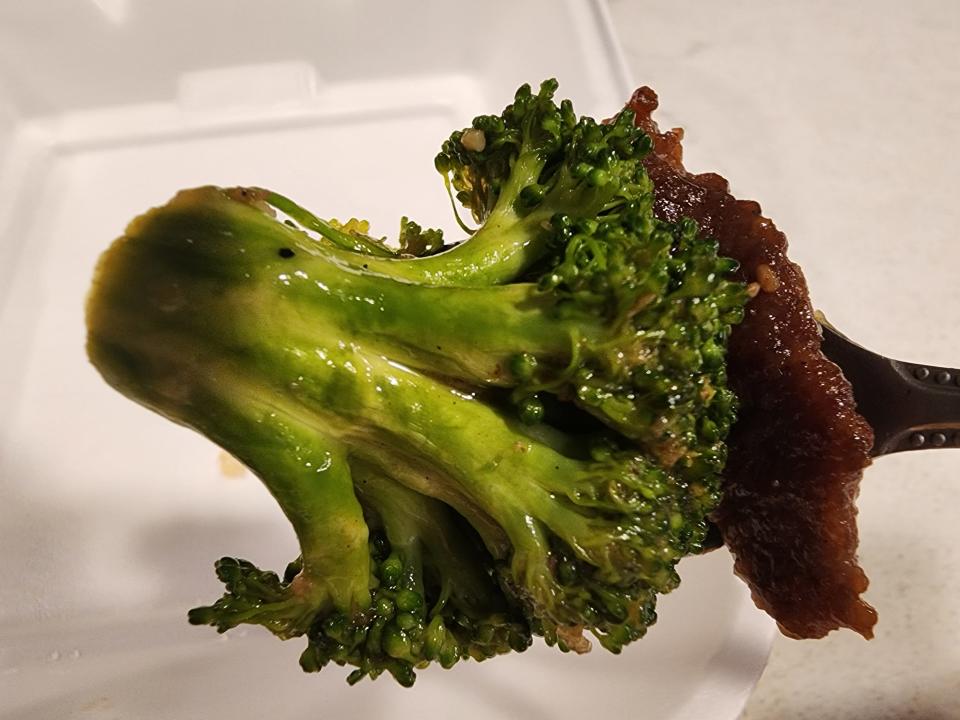 A broccoli floret and a piece of beef on a fork