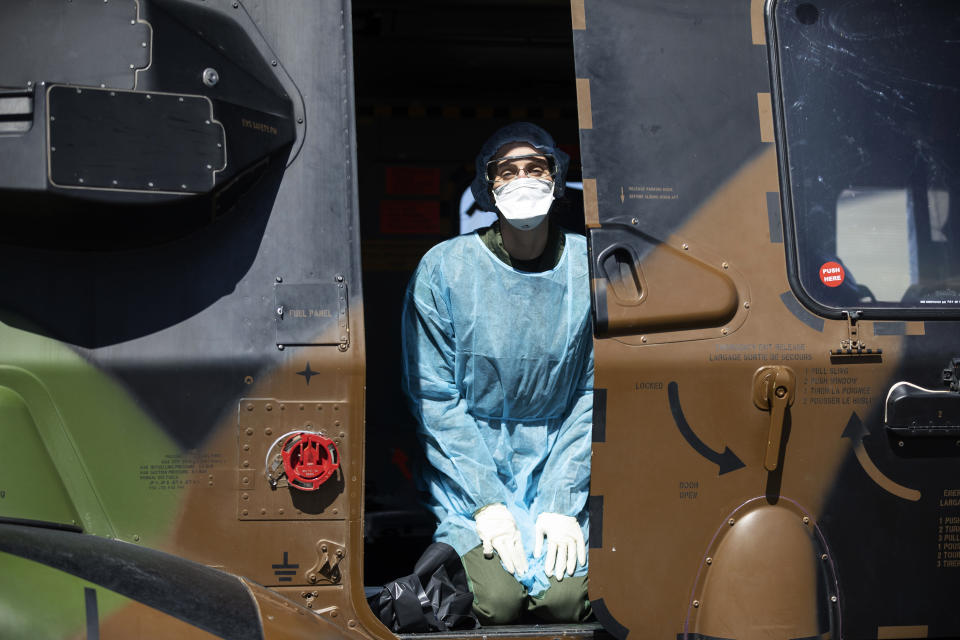 A medical staff kneels in a French military helicopter before evacuating to Switzermand a patient infected with the Covid-19 virus, Monday, March 30 2020 in Strasbourg, eastern France. The new coronavirus causes mild or moderate symptoms for most people, but for some, especially older adults and people with existing health problems, it can cause more severe illness or death.