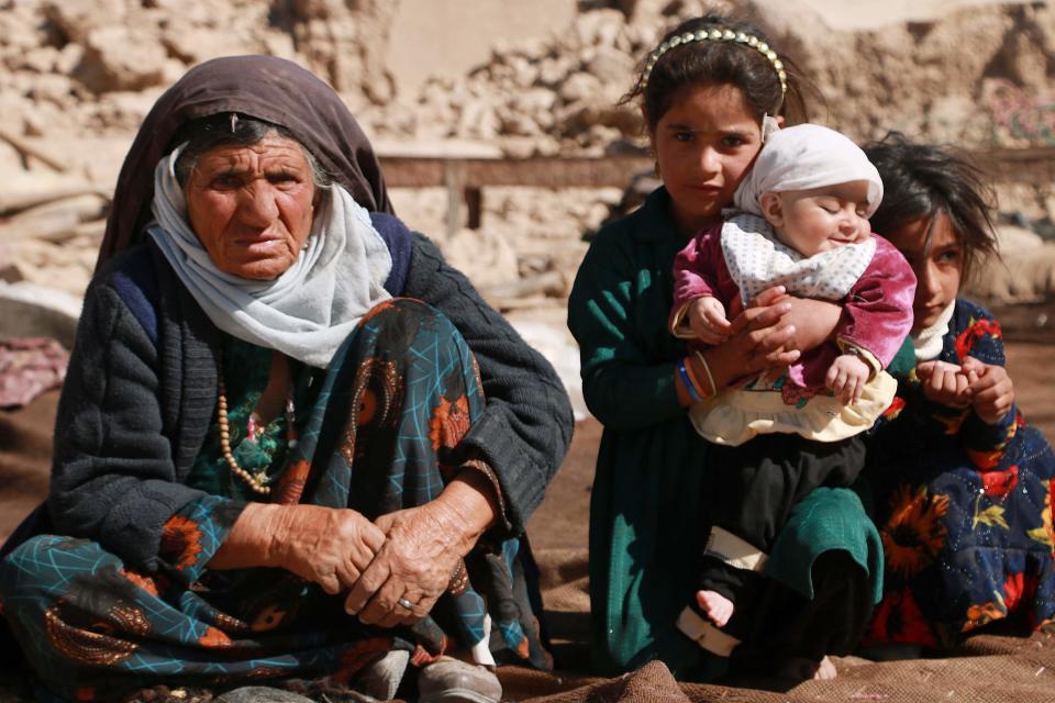 Afghan people sit outside a makeshift shelter in Chahak village in Injil district of Herat province on October 24, 2023, after a magnitude 6.3 earthquake shook western Afghanistan on October 15.