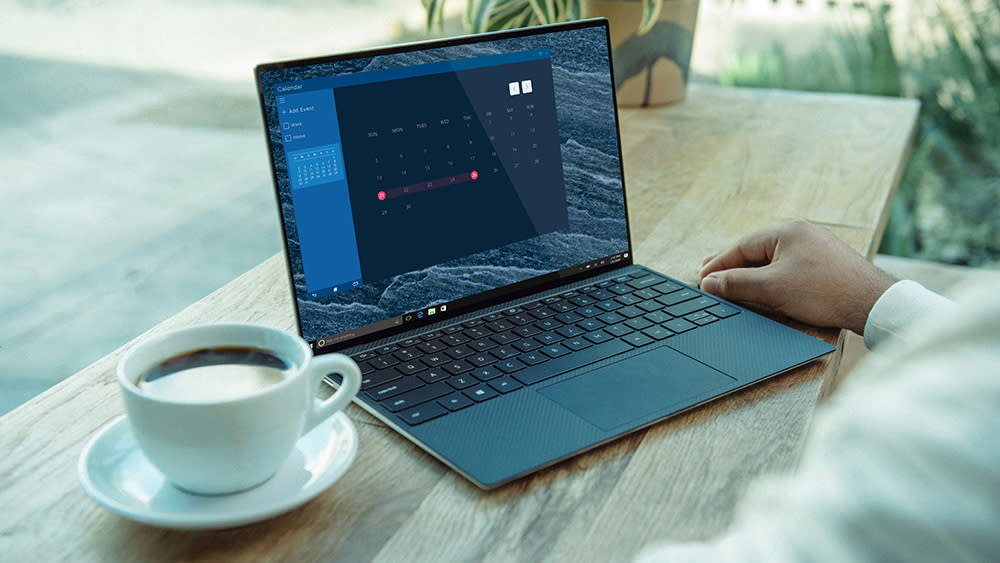  A man learns how to install apps on a laptop, with a Windows laptop on a table beside a cup of coffee. 