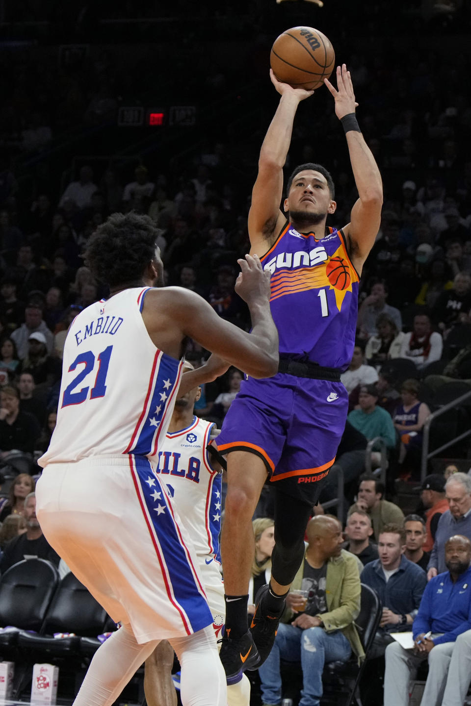 Phoenix Suns guard Devin Booker shoots over Philadelphia 76ers center Joel Embiid (21) during the second half of an NBA basketball game Saturday, March 25, 2023, in Phoenix. The Suns won 125-105. (AP Photo/Rick Scuteri)