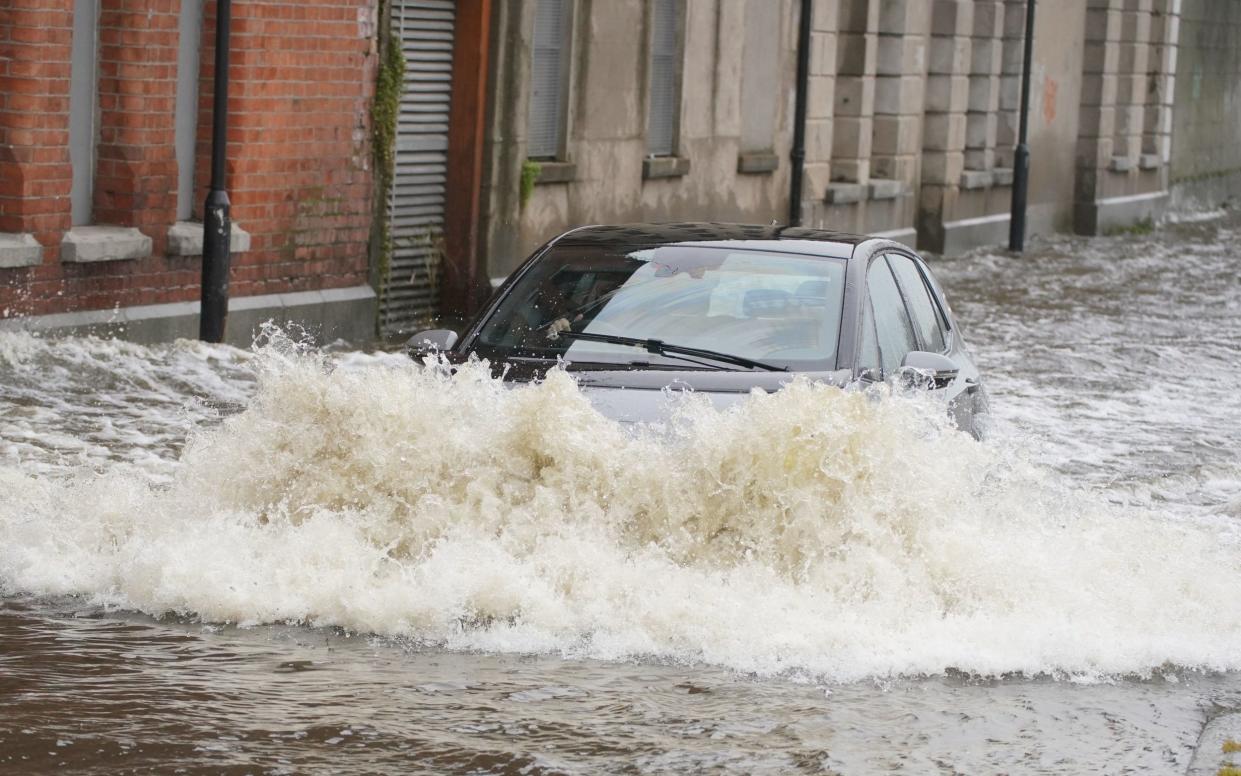 A car drives through flood water on Canal Quay in Newry Town, Co Down, which has been swamped by floodwater as the city's canal burst its banks amid heavy rainfall. Dozens of businesses were engulfed in the floods, with widespread damage caused to buildings, furnishings and stock. Picture date: Wednesday November 1, 2023