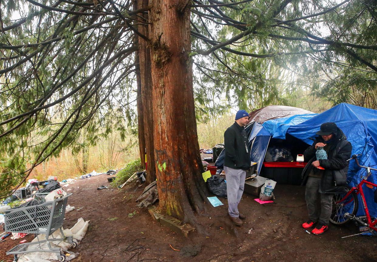 Jarrod Moran, coordinator of Kitsap County's HEART team, talks with Aaron Phillips, right, as he gets ready to leave the encampment in the woods in the Hospital Hill area of the Clear Creek Trail in Silverdale on Wednesday. A few of the last residents in the encampment were packing and moving their things as the county began to clean up the area after closing the encampment.