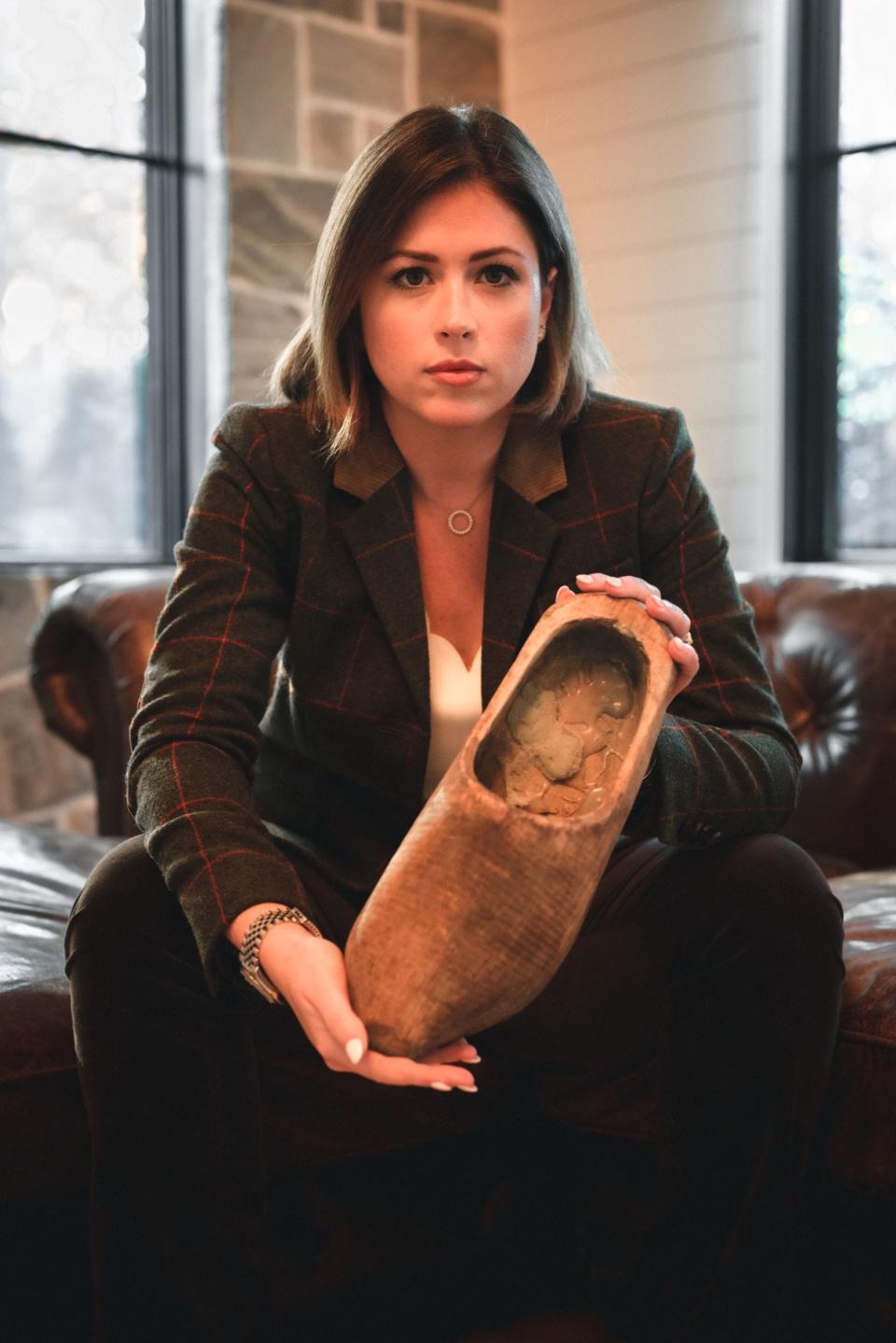 CNN entertainment reporter Chloe Melas holds one of the wooden shoes that her grandfather, Frank Murphy, wore during a forced march from a prisoner of war camp in January 1945.