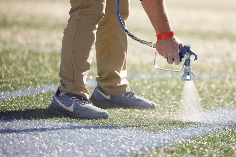 Casey Carrick, a member of the UNC grounds crew who lives in Raleigh, works to paint the field for the ACC Championship football game against Clemson at Bank of America Stadium in December 2022.