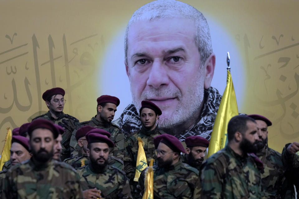 Hezbollah fighters stand next to a poster of their comrade, senior commander Mohammad Naameh Nasser, who was killed by an Israeli airstrike that hit his car in the southern costal town of Tyre, during his funeral procession in the southern suburbs of Beirut, Lebanon, Thursday, July 4, 2024. (AP Photo/Bilal Hussein)