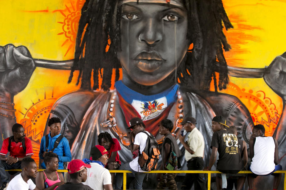 In this Oct. 29, 2019 photo, protesters gather in front of a mural depicting justice as equality, under a bridge in the Delmas community of the district of Port-au-Prince, Haiti. Anger over corruption, inflation and scarcity of basic goods, including fuel, has led to more than a month of demonstrations that have paralyzed the country as protesters demand the resignation of President Jovenel Moïse. (AP Photo/Dieu Nalio Chery)