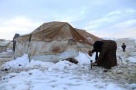 A displaced Syrian woman sets up her tent at a refugee camp, in Afrin, north of Aleppo, Syria, Wednesday, Jan. 19, 2022. A snowstorm in the Middle East has left many Lebanese and Syrians scrambling to find ways to survive. Some are burning old clothes, plastic and other hazardous materials to keep warm as temperatures plummet and poverty soars. (AP Photo/Ghaith Alsayed)