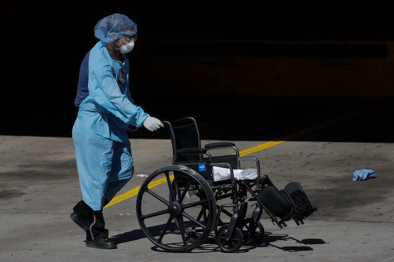 Healthcare worker with empty wheelchair outside Wyckoff Heights Medical Center during outbreak of coronavirus disease (COVID-19) in New York