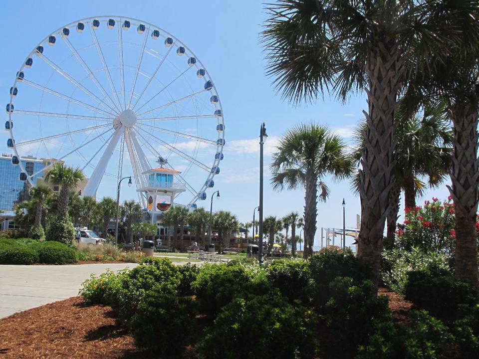 This May 22, 2013 photo shows Plyler Park, just off the boardwalk in Myrtle Beach, S.C. During the summer season, the park is the site of the Hot Summer Nights series of concerts and other events. In the background is the SkyWheel, the tallest Ferris wheel in the eastern United States. (AP Photo/Bruce Smith)