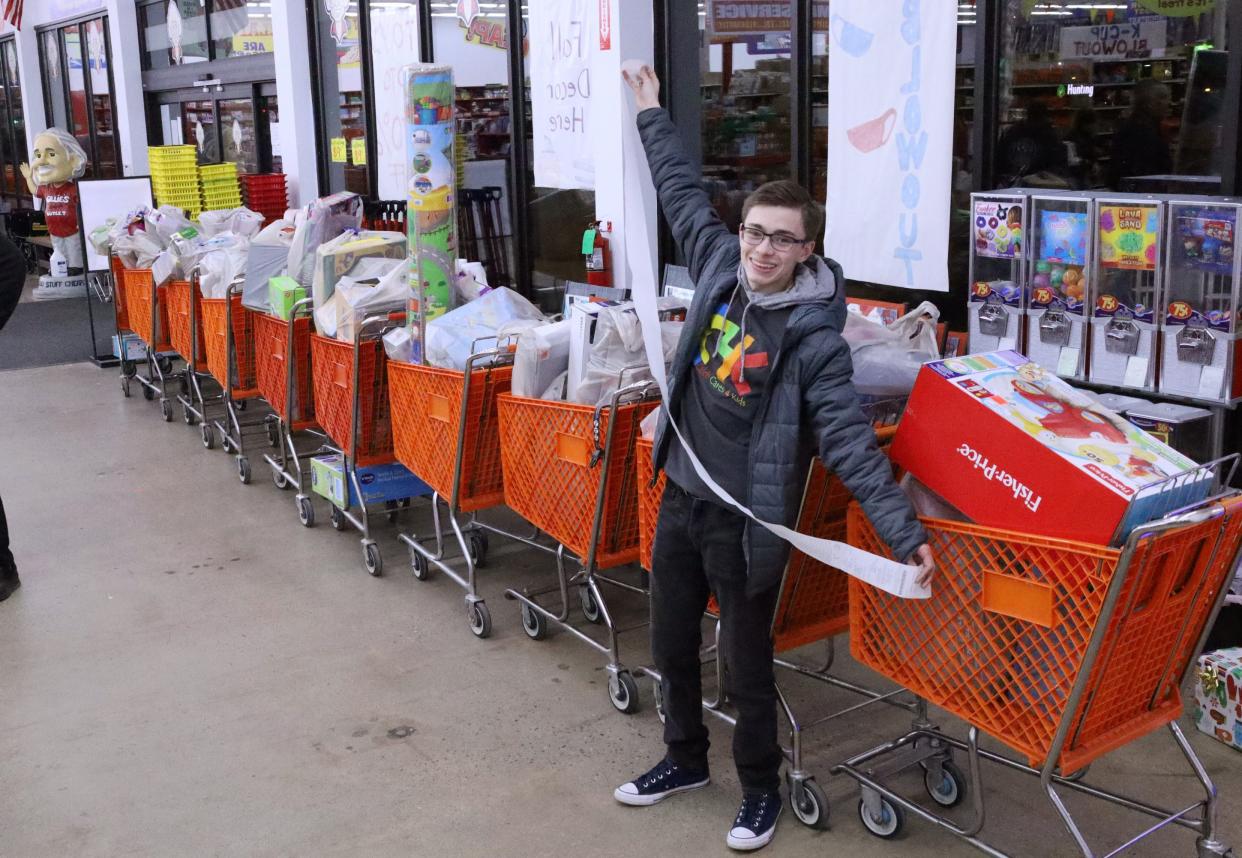 Caleb Silvia shows the length of the receipt after buying nine shopping carts worth of toys at Ollie's in South Zanesville for his charity, Caleb Cares 4 Kids.