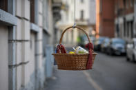 One of the baskets with food and other goods hanging from balconies and left at disposition of people in need during the coronavirus emergency in Milan, Italy, Saturday, April 4, 2020. The initiative, dubbed "hanging baskets", was born after an old Neapolitan tradition, that of the "hanging coffee" (Caffe' sospeso) that customers pay in bars and are left at disposition of whoever enters the bar and asks for it. The new coronavirus causes mild or moderate symptoms for most people, but for some, especially older adults and people with existing health problems, it can cause more severe illness or death. (Claudio Furlan/LaPresse via AP)