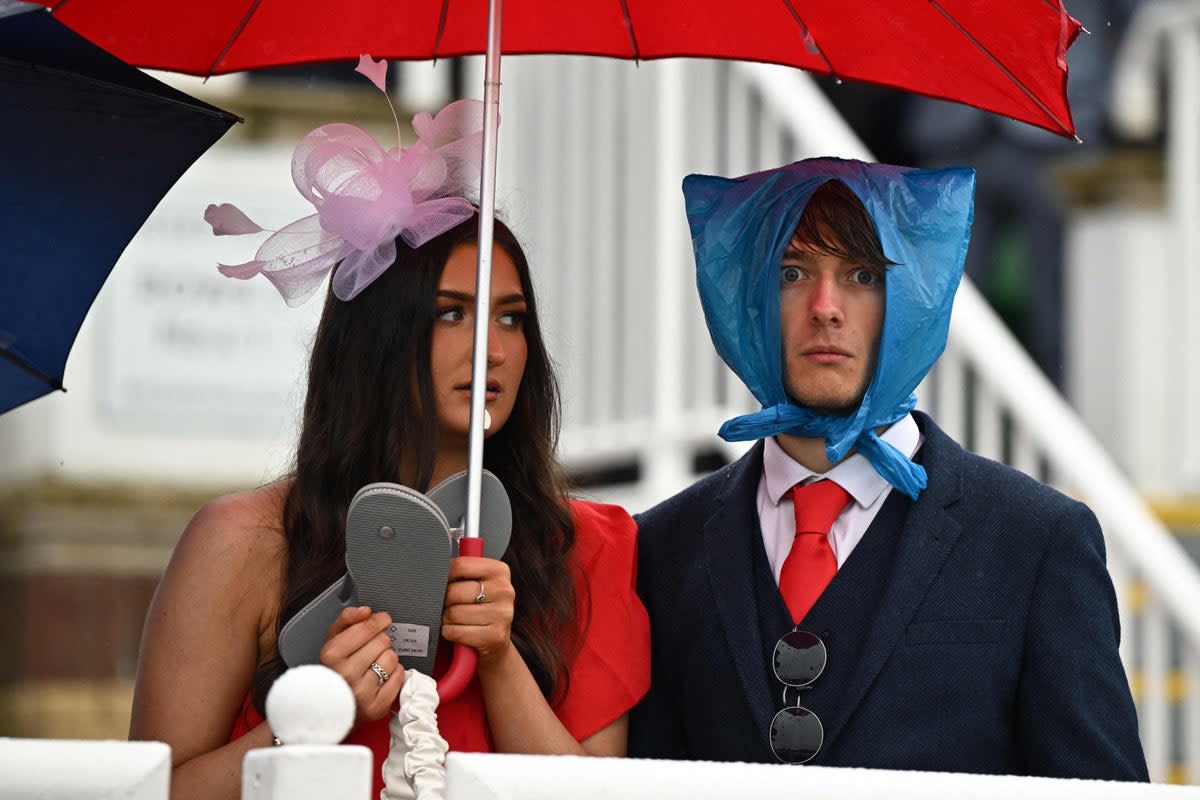 Racegoers shelter from the rain as they attend on the second day of the Grand National Festival horse race meeting at Aintree Racecourse in Liverpool, north-west England (AFP/Getty)