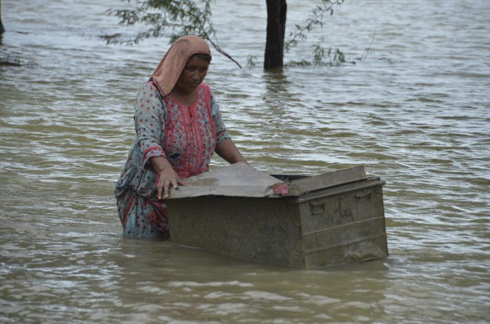 A woman uses a trunk to salvage usable items from her flood-hit home in Jaffarabad, a district of Pakistan's southwestern Baluchistan province, Thursday, Aug. 25, 2022. Pakistan's government in an overnight appeal sought relief assistance from the international community for flood-affected people in this impoverished Islamic nation, as the exceptionally heavier monsoon rain in recent decades continued lashing various parts of the country. (AP Photo/Zahid Hussain)
