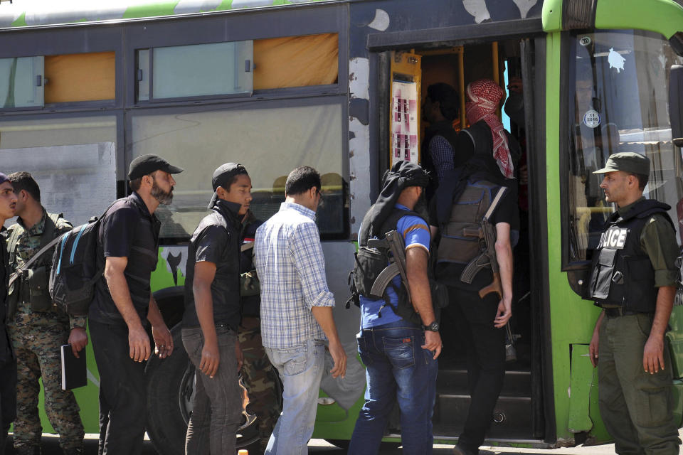 FILE - In this file photo released by the Syrian official news agency SANA on Sept. 26, 2016, anti-Syrian government fighters, left, some of them carrying their weapons, head to a bus as they leave the last besieged rebel-held neighborhood of Al-Waer in Homs province, Syria. In the northern Idlib province, a corner of nearly 3 million people, the government and its opponents are preparing for a final, bloody showdown. In the last year alone, the government has forced its opponents out of Damascus, Homs, Daraa, and Quneitra, four provinces and cities that were longtime opposition strongholds. (SANA via AP, File)