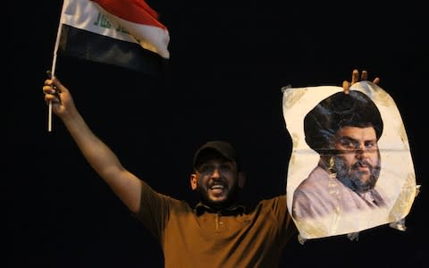 An Iraqi man celebrates with a picture of Shia cleric Moqtada al-Sadr in Baghdad - Credit: AFP