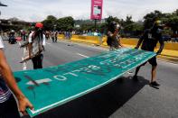 <p>Opposition supporters carry materials to build a barricade to block an avenue while rallying against President Nicolas Maduro in Caracas, Venezuela, May 15, 2017. (Carlos Garcia Rawlins/Reuters) </p>