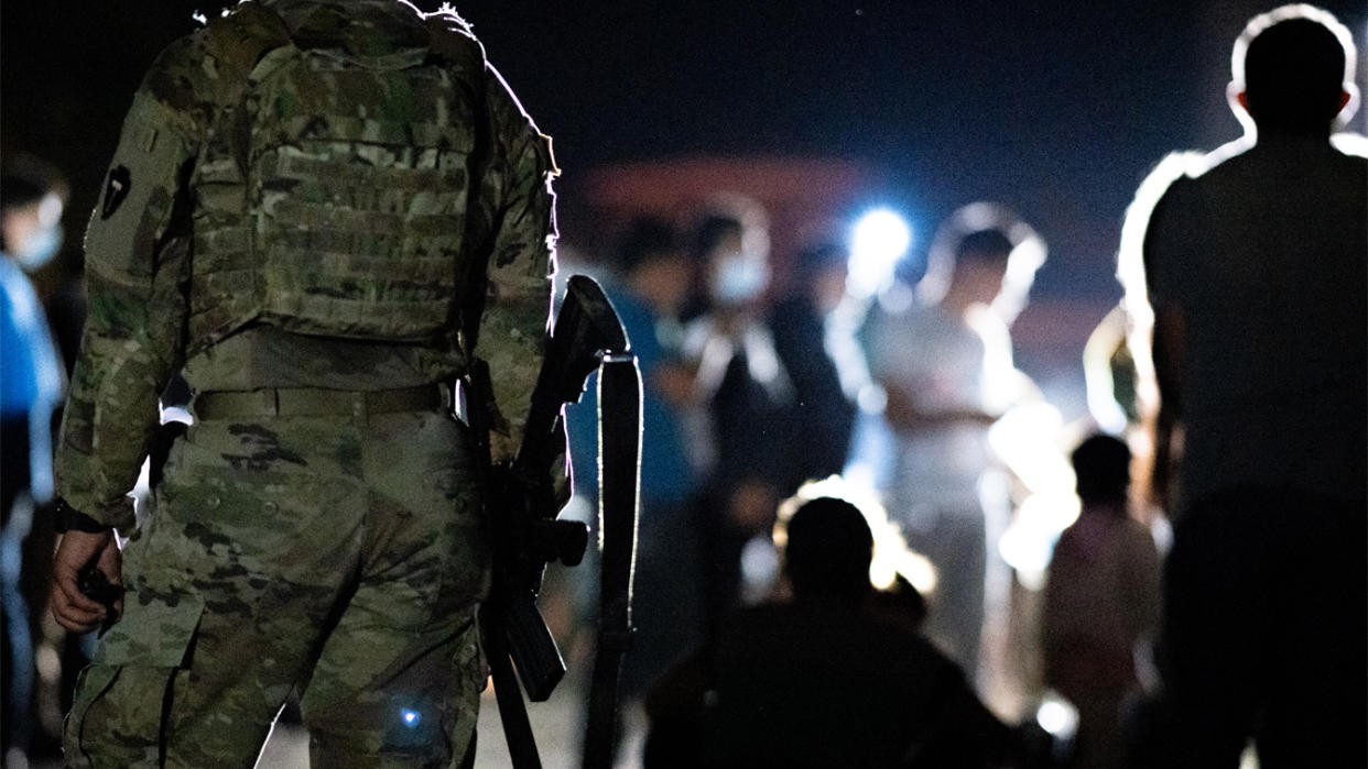 A member of the National Guard stand watch while immigrants wait to be processed after crossing the Rio Grande into the U.S. on June 16, 2021 in Roma, Texas. (Brandon Bell/Getty Images)