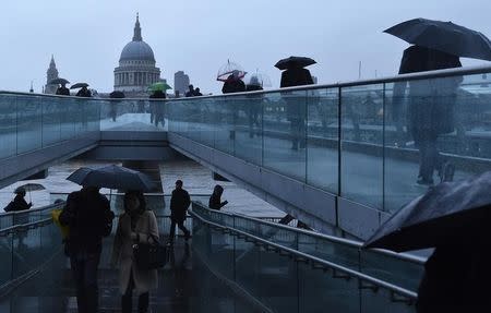 City workers cross the Millennium footbridge at dawn in front of St Paul's Cathedral in London, Britain January 7, 2016. REUTERS/Toby Melville