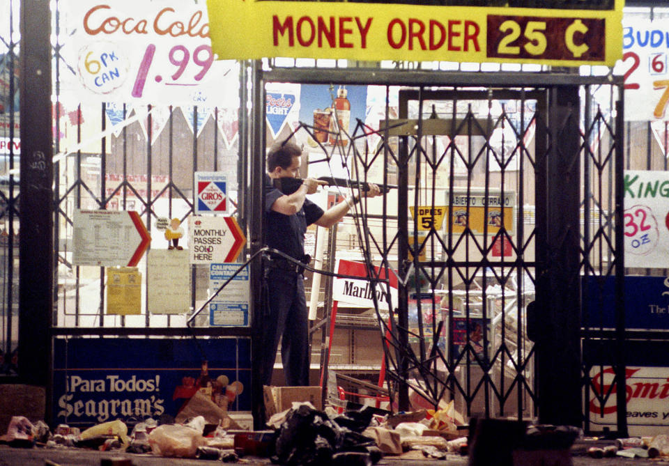 FILE - In this April 30, 1992 file photo, a Los Angeles police officer takes aim at someone attempting to steal something from a market in Los Angeles during the second night of rioting in the city in response to the acquittal of four police officers in the videotaped beating of Rodney King. (AP Photo/John Gaps III, File)