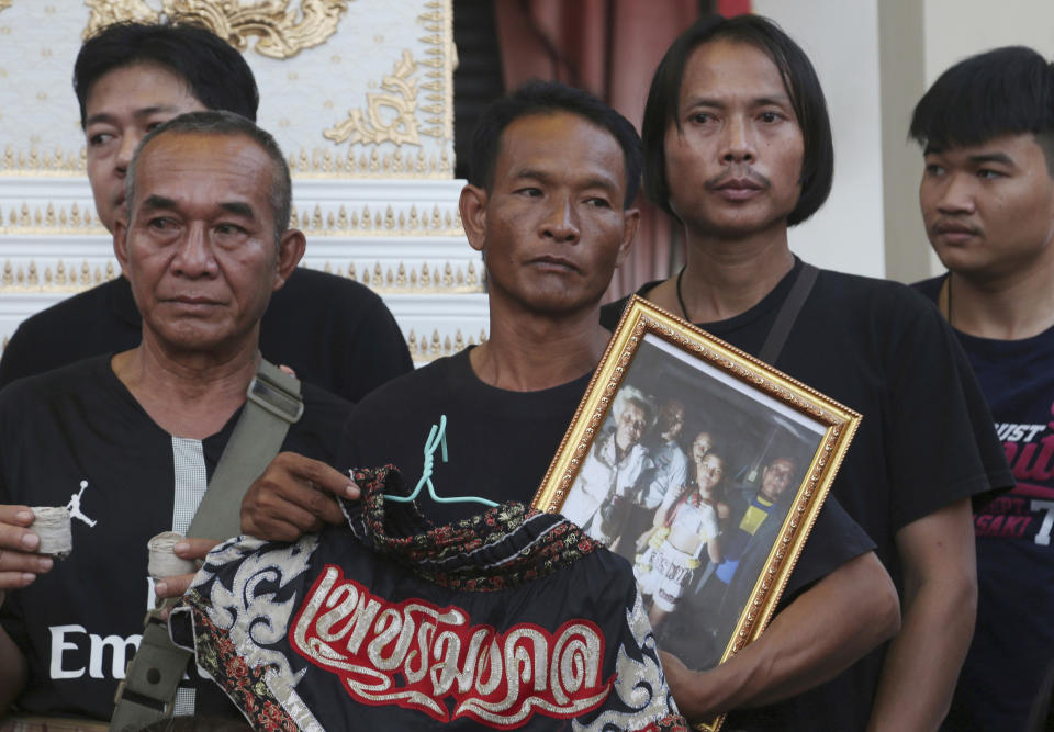 In this Thursday, Nov. 15, 2018, photo, relatives of 13-year-old Thai kickboxer Anucha Tasako hold his boxing shorts and a portrait during his funeral services in Samut Prakan province, Anucha died of a brain hemorrhage two days after he was knocked out in a bout on Nov. 10 that was his 174th match in the career he started at age 8. Thai lawmakers recently suggested barring children younger than 12 from competitive boxing, but boxing enthusiasts strongly oppose the change. (AP Photo/Sakchai Lalit)