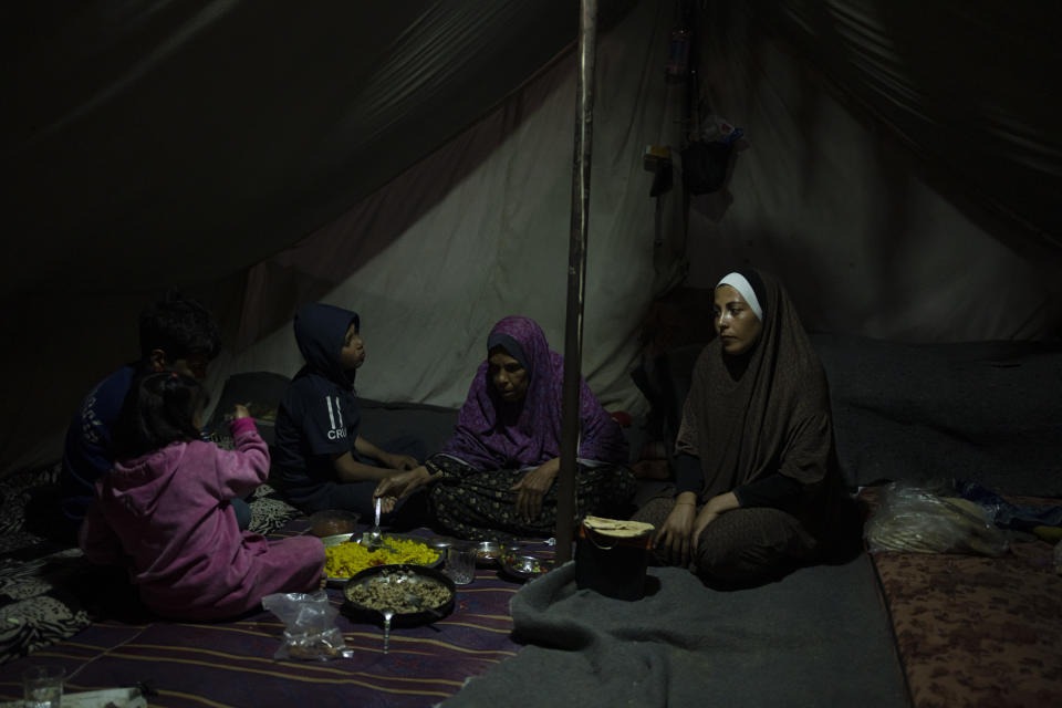 Randa Baker, Right, and her family, who were displaced by the Israeli bombardment of the Gaza Strip, break their fast on the first day of the Muslim holy fasting month of Ramadan at a makeshift tent camp in the Muwasi area, southern Gaza, March 11, 2024. The holy month, typically a time of communal joy and reflection, is overshadowed by the grim reality of a conflict that has claimed over 30,000 Palestinian lives and left vast swaths of Gaza in shambles. (AP Photo/Fatima Shbair)