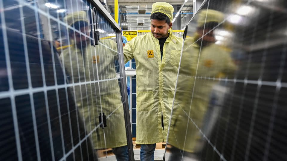 An employee inspecting solar panels at an Adani Group factory in Mundra. - Punit Paranjpe/AFP/Getty Images