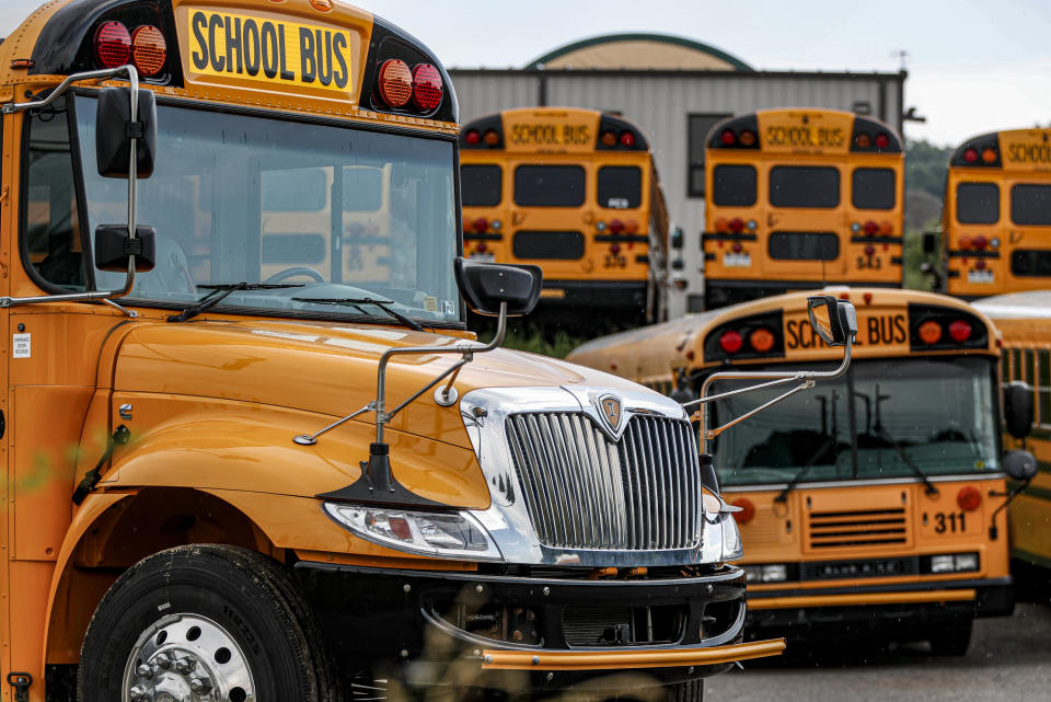 FILE - In this Friday, July 10, 2020, file photo, rows of school buses are parked at their terminal, in Zelienople, Pa. Reopening schools during the coronavirus pandemic means putting children on school buses, and districts are working on plans to limit the risk. (AP Photo/Keith Srakocic, File)