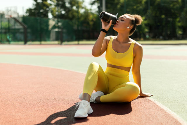 woman drinking water or protein, taking break after outdoors exercise