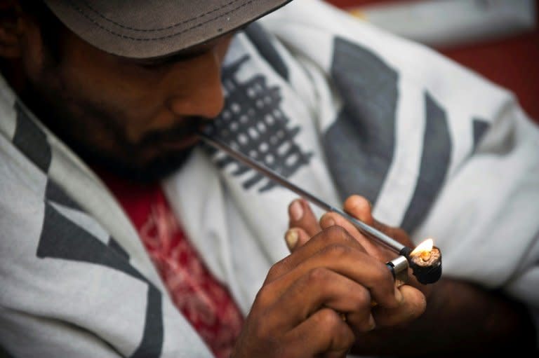 A drug addict lights an improvised pipe on the street in