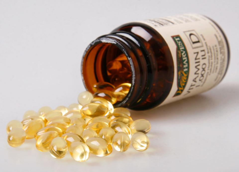 A bottle of vitamin D with capsules spilling out.