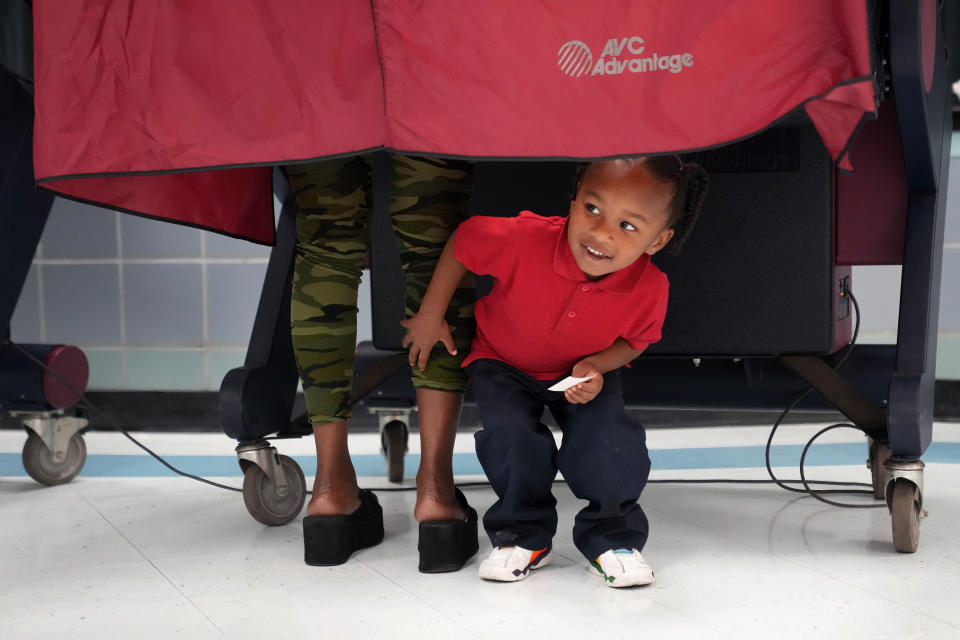 Kash Strong, 3, peeks out from under the curtain of a voting booth as his mother Sophia Amacker casts her vote on Election Day at the Martin Luther King Elementary School in the Lower Ninth Ward of New Orleans, Tuesday, Nov. 8, 2022. (AP Photo/Gerald Herbert)