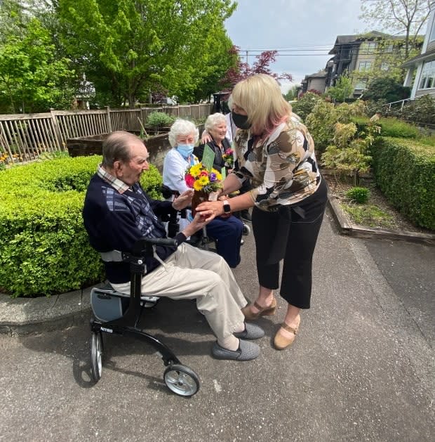 Treena Innes, right, founder of Bouquets for Baba, hands a surprise gift of flowers to isolated seniors in Maple Ridge, B.C. She launched the initiative to let seniors know they are cared for. (Greg Rasmussen/CBC - image credit)