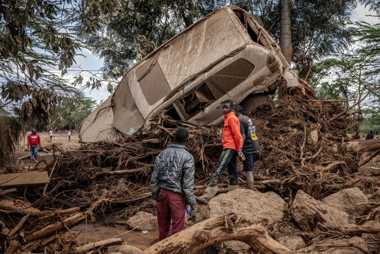 Young men inspect a destroyed car carried by waters in an area heavily affected by torrential rains and flash floods in the village of Kamuchiri, near Mai Mahiu, on April 29, 2024