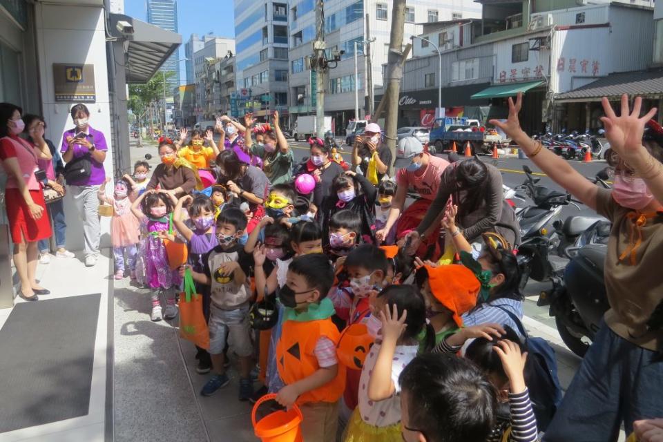 新北市八里教養院三重日托慢飛天使與威妮斯特堡幼兒園昨萬聖節前夕變裝踩街，到某家銀行前搗蛋討糖吃。（記者吳瀛洲攝）