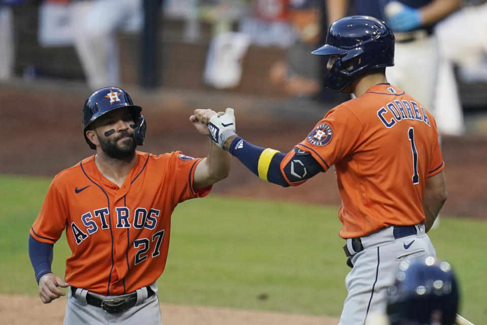 El venezolano José Altuve festeja con el puertorriqueño Carlos Correa, de los Astros de Houston, luego de anotar en el sexto juego de la Serie de Campeonato de la Liga Americana, frente a los Rays de Tampa Bay, el viernes 16 de octubre de 2020 , en San Diego (AP Foto/Gregory Bull)