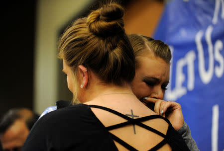 Laura Grillot (L) consoles her sister Maggie, after their brother Ian Grillot was injured trying to stop a gunman who killed Indian engineer Srinivas Kuchibhotla at a local bar, during a vigil at a conference center in Olathe, Kansas, U.S., February 26, 2017. REUTERS/Dave Kaup