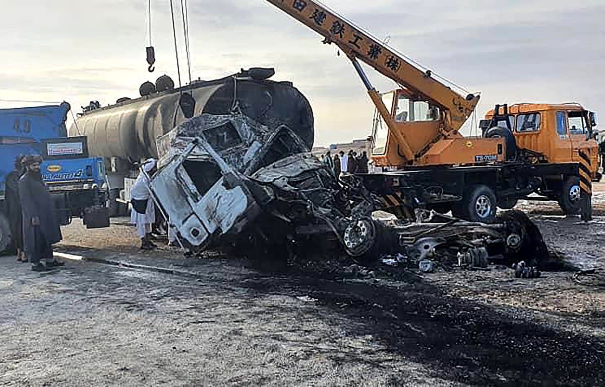 Security personnel and volunteers standing near the wreckage of burned passenger bus and oil tanker on the Herat-Kandahar highway in Grishk district of Helmand province (Afghanistan’s Helmand Information Department/AFP via Getty Images)