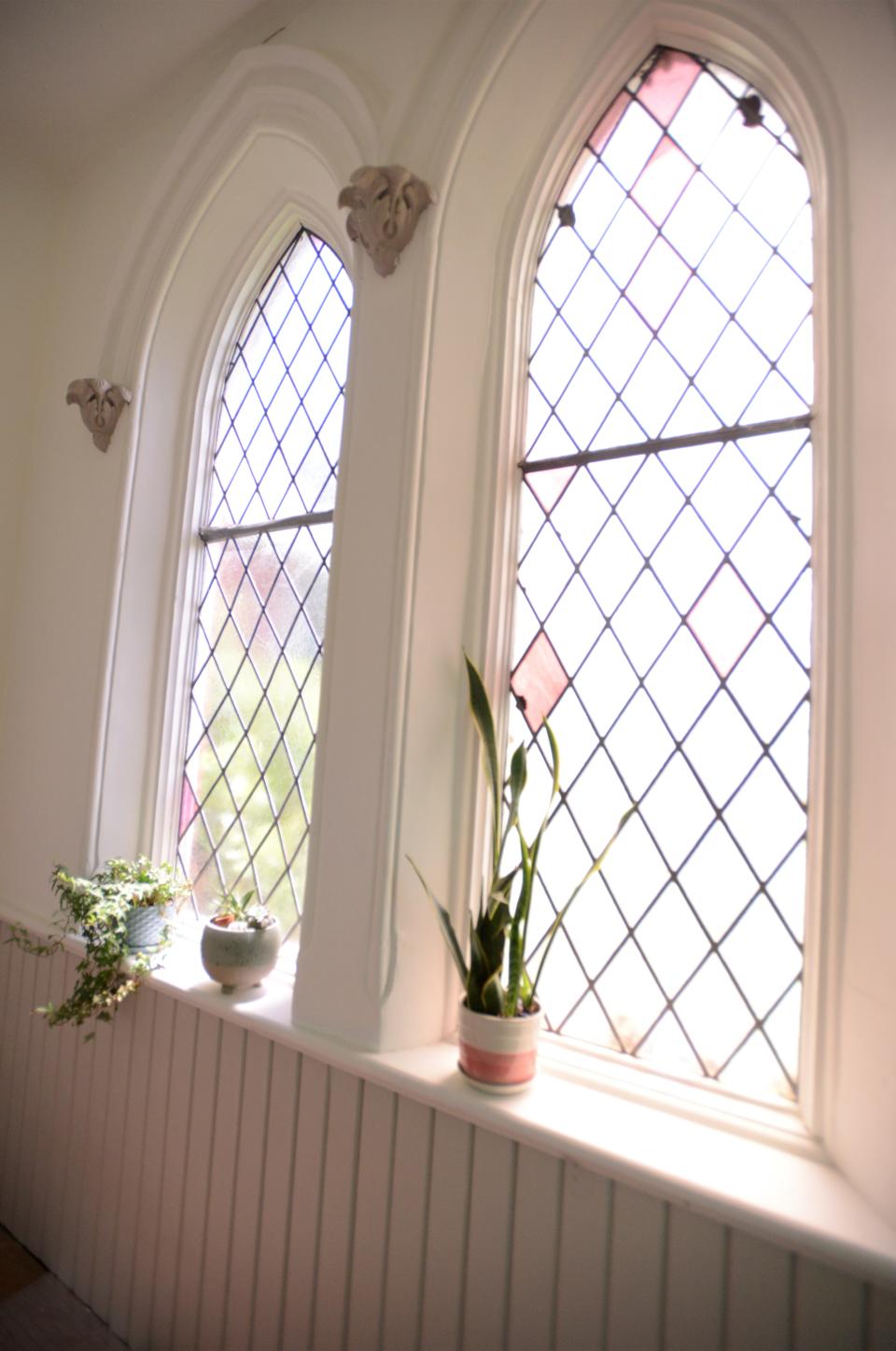 The stained glass windows fill the home with a pinkish light.