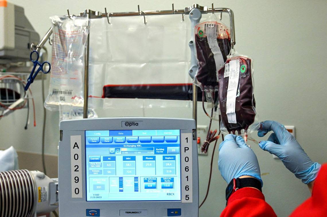 A worker from the Community Blood Center hangs a bag of blood during a transfusion for Kevin Wake at the Sickle Cell Center at University Health.