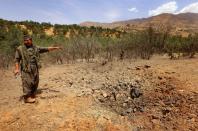 A member of the Kurdistan Workers' Party (PKK) inspects a crater reportedly caused by an air strike from Turkish warplanes on July 29, 2015 in the Qandil mountain