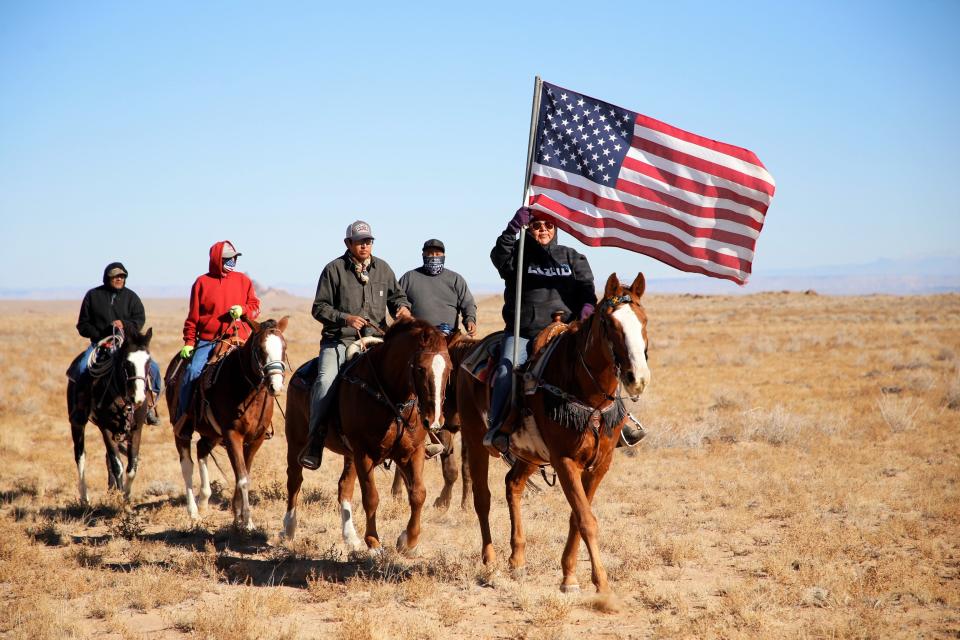 Elvira Arviso carries the flag of the United States during the T'oAltsisi Horseback Trail Ride, an event that honors the service of veterans, on Nov. 11 north of Littlewater.