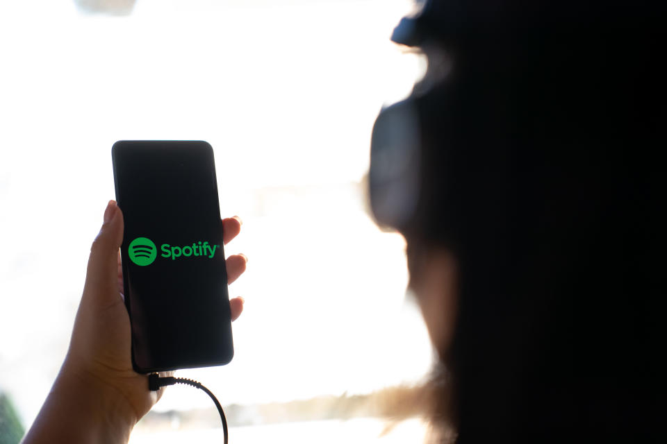 A woman holding a mobile phone with the logo of Spotify on its screen. (Photo by Nikos Pekiaridis/NurPhoto via Getty Images)