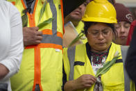 Construction workers and supporters hold flowers during a moment of prayer at a vigil and press conference by CASA of Maryland, a community advocacy group, to remember the six workers killed in the collapse of the Francis Scott Key Bridge and to highlight the difficult conditions faced by immigrant construction workers on Friday, March 29, 2024, in Baltimore, Md. (AP Photo/Mark Schiefelbein)