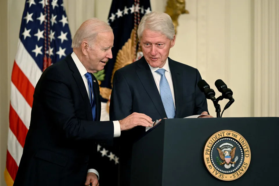US President Joe Biden helps former US President Bill Clinton find his notes during an event marking the 30th Anniversary of the Family and Medical Leave Act, in the East Room of the White House in Washington, DC, on February 2, 2023. (Photo by Andrew CABALLERO-REYNOLDS / AFP) (