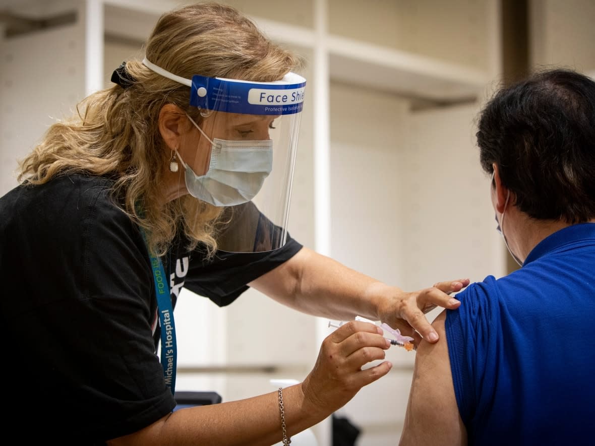 A health care provider with Unity Health Toronto administers the Pfizer-BioNTech COVID-19 vaccine at a one-day pop-up clinic in the Eaton Centre mall in Toronto on July 27, 2021. (Evan Mitsui/CBC - image credit)